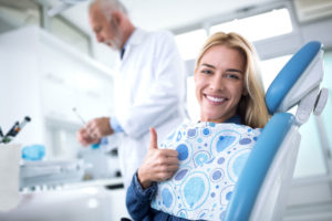 Happy dental patient gives a thumbs up.