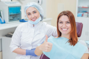 Dentist and a happy patient giving a thumbs up.