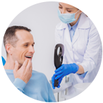 Dental Patient Observing His New Smile As Doctor Holds Up a Mirror